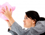 Woman trying to take money out of a piggybank